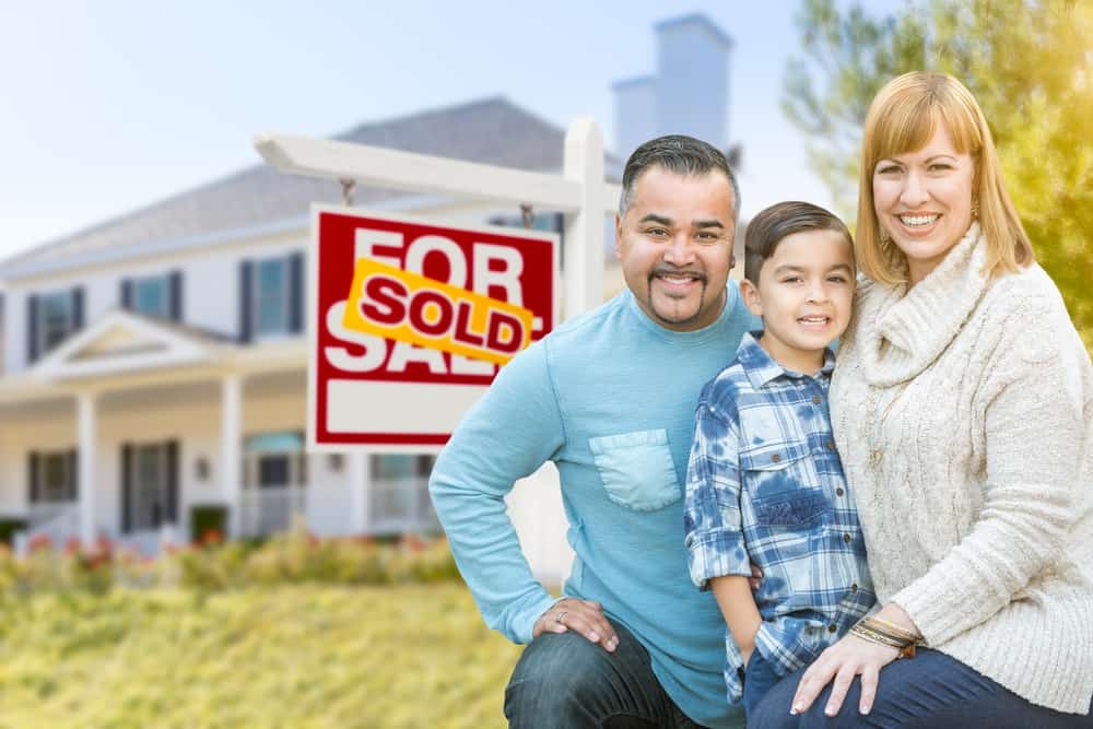 A family in front of of a sold property