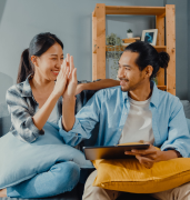 happy-asian-young-attractive-couple-man-woman-sit-couch-use-tablet-shopping-online-furniture-new-house-min 1